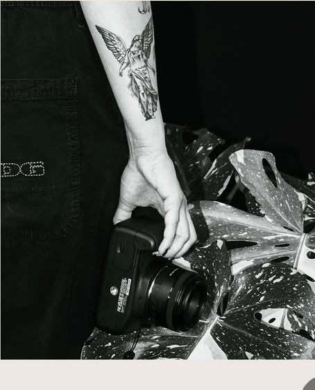 Nadine’s tattooed arm reaching for a camera