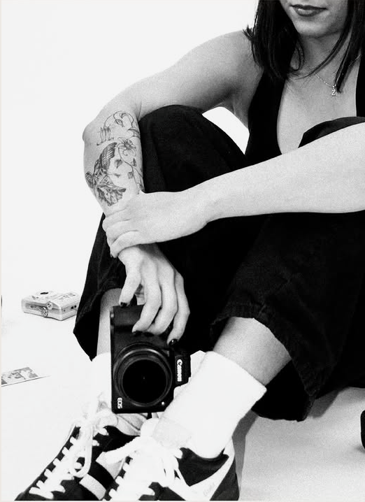 Nadine seated with a camera in a South Texas studio portrait